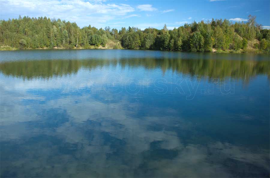 Облака отражаются в воде лесного озера
